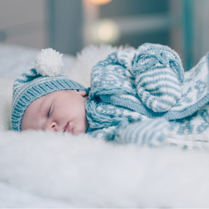 Hentetsettet velkommen til verden er en strikkepakke til baby. Her ser vi bildet av babyen som ligger på siden med ansiktet vendt mot kamera. Bildet er fra midjen og opp.